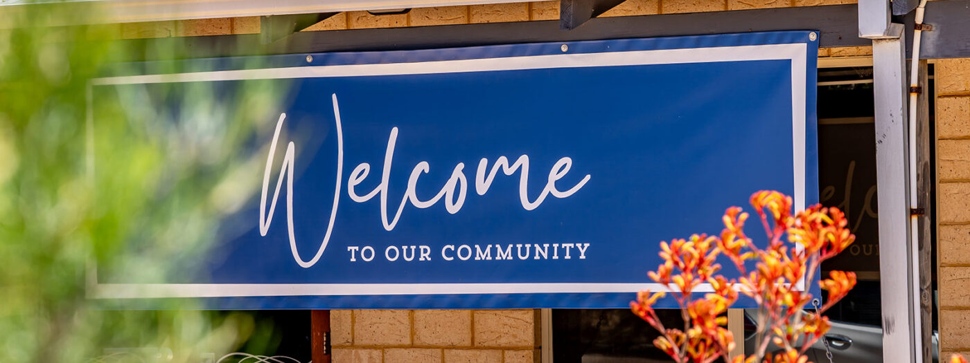 Blue Sign with white letters at Waratah Community Village that says Welcome To Our Community
