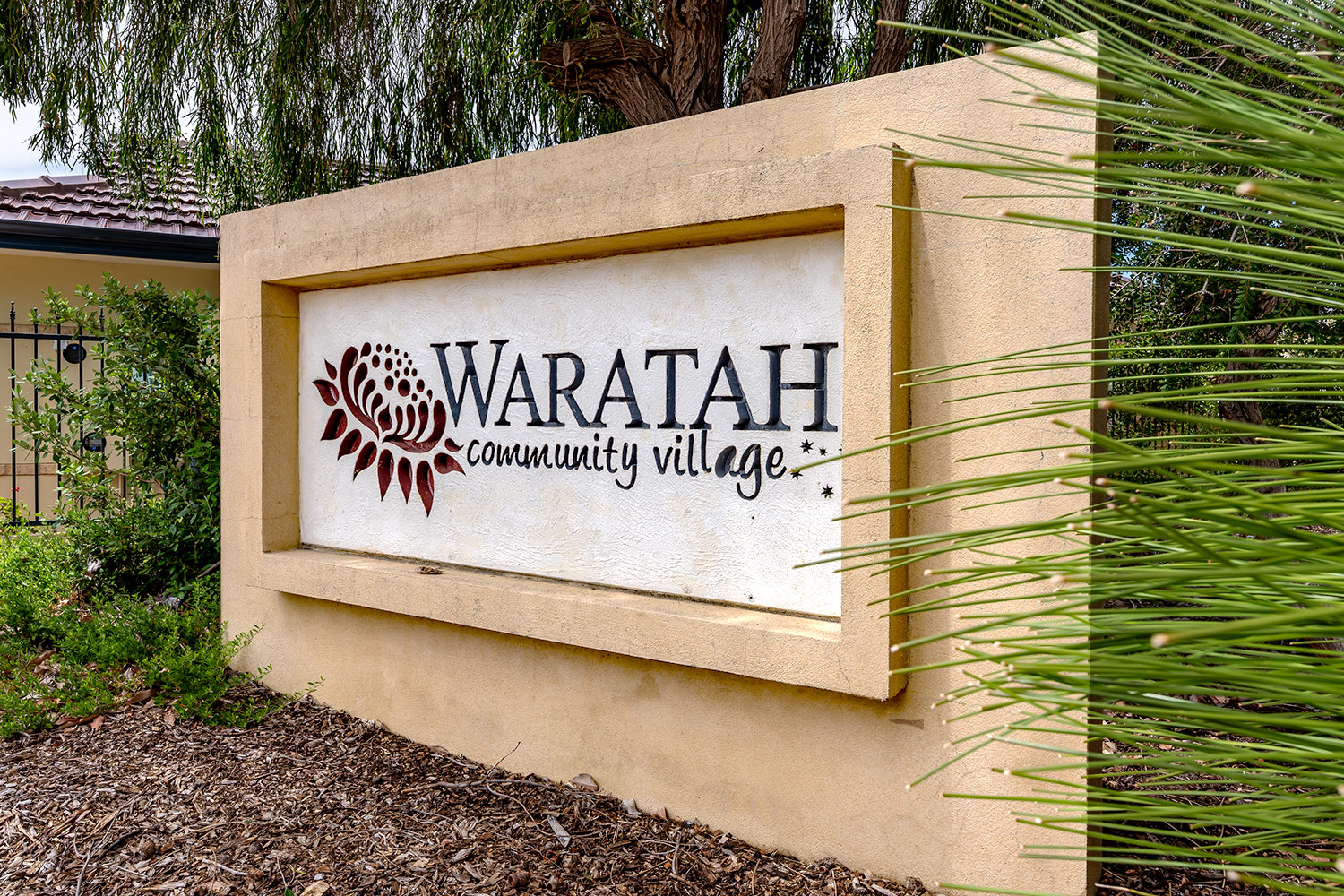 Large entrance sign with the words Waratah Community Village logo
